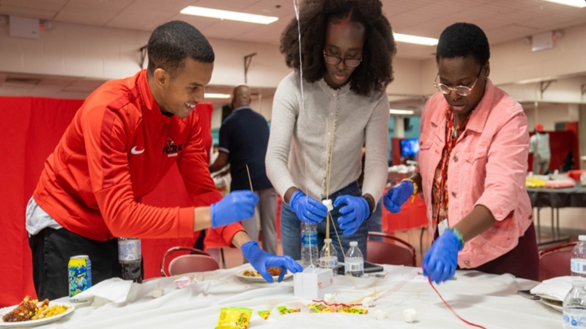 Students collaborate on team building activity experiment.