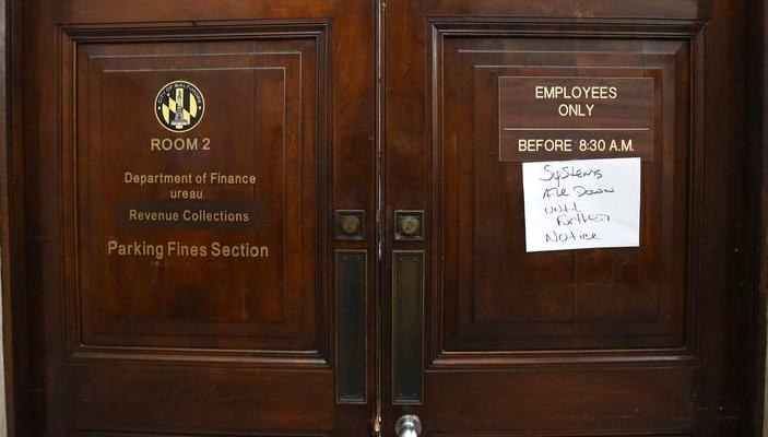 Image of entrance to Baltimore Department of Finance and Revenue Collections with a systems all down notice on the door.