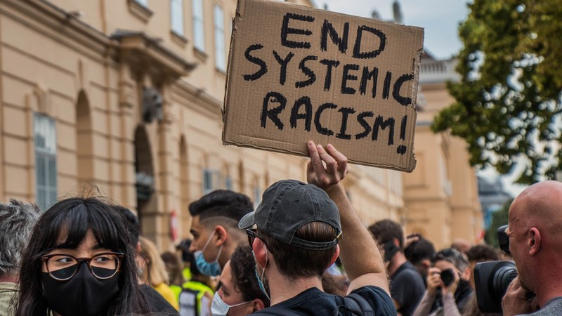 The person holding a sign that reads "end Systemic Racism"