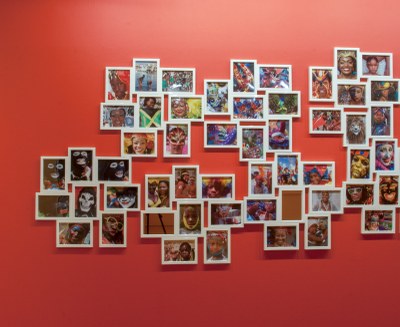 large number of small photographs as installed in a cluster in the gallery, left portion